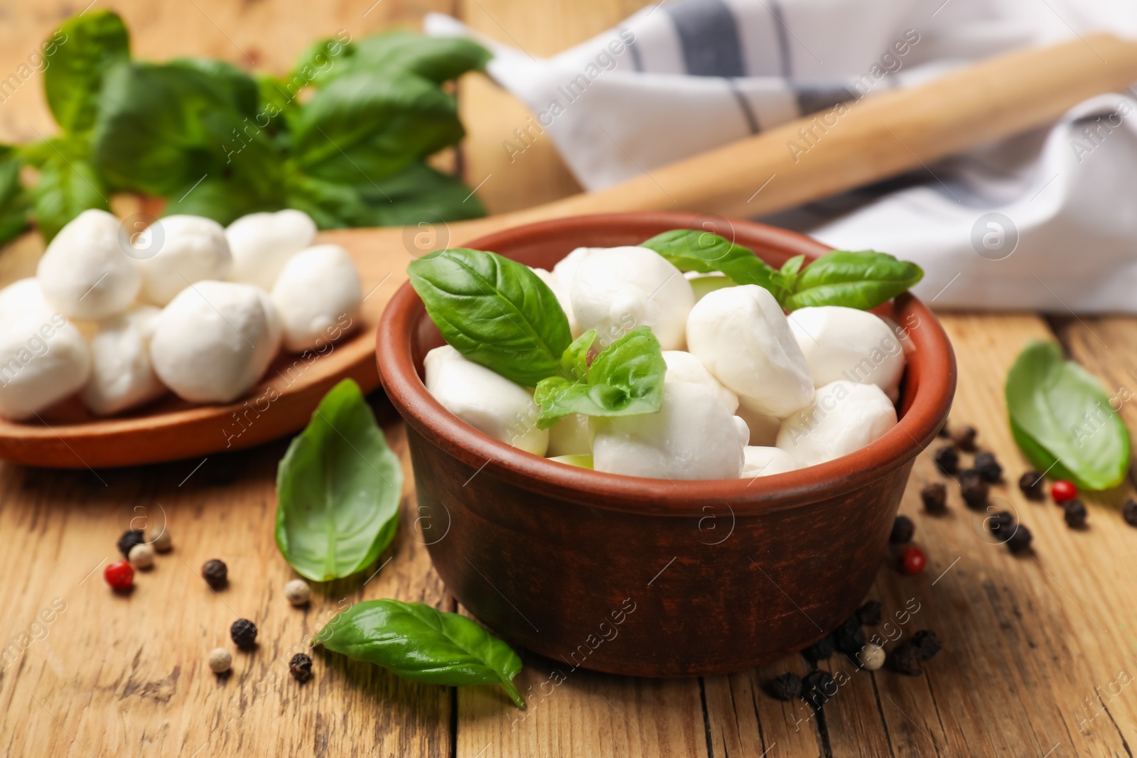 Mozzarella cheese balls with basil and peppercorns on wooden table, closeup Photo of Mozzarella cheese balls with basil and peppercorns on wooden table, closeup