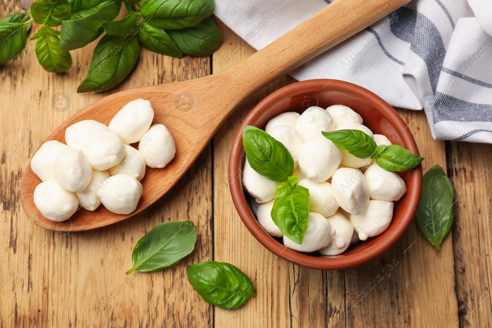 Mozzarella cheese balls and basil on wooden table, flat lay Photo of Mozzarella cheese balls and basil on wooden table, flat lay