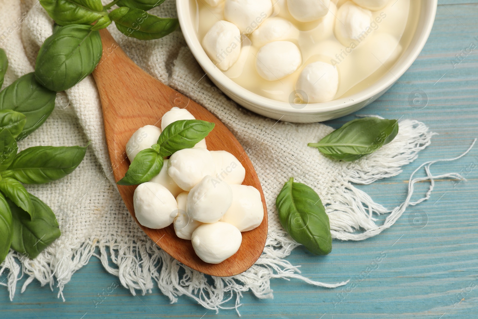 Mozzarella cheese balls and basil on blue wooden table, flat lay Photo of Mozzarella cheese balls and basil on blue wooden table, flat lay