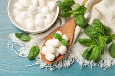 Photo of Mozzarella cheese balls and basil on blue wooden table, flat lay