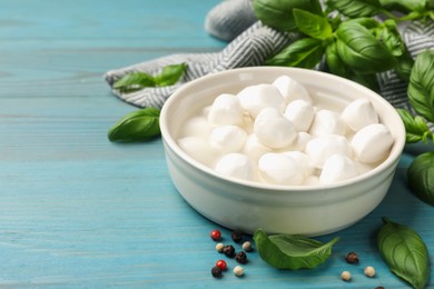 Photo of Mozzarella cheese balls with basil and peppercorns on blue wooden table, closeup. Space for text