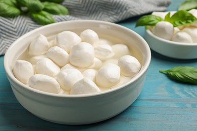Photo of Mozzarella cheese balls and basil on blue wooden table, closeup