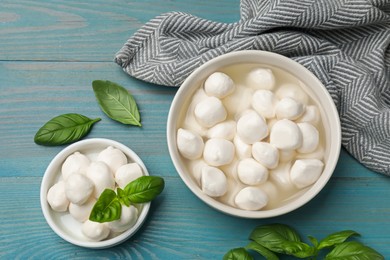 Photo of Mozzarella cheese balls and basil on blue wooden table, flat lay