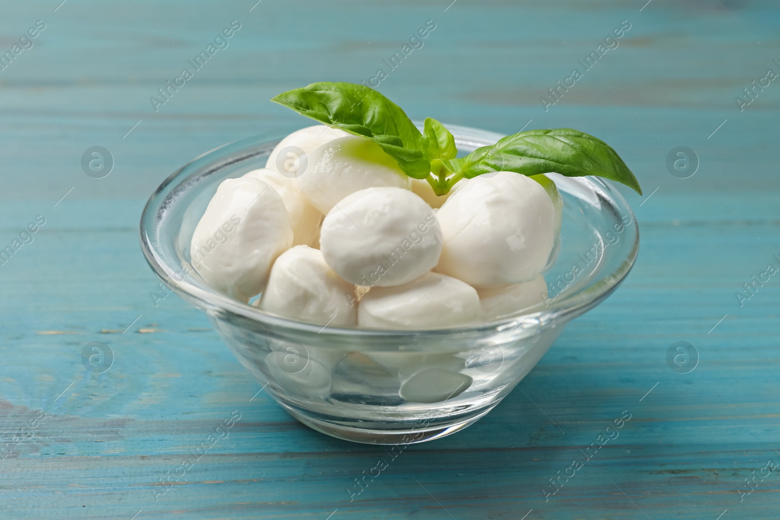 Mozzarella cheese balls and basil on blue wooden table, closeup Photo of Mozzarella cheese balls and basil on blue wooden table, closeup