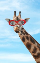 Image of Cute giraffe with sunglasses against blue sky with clouds