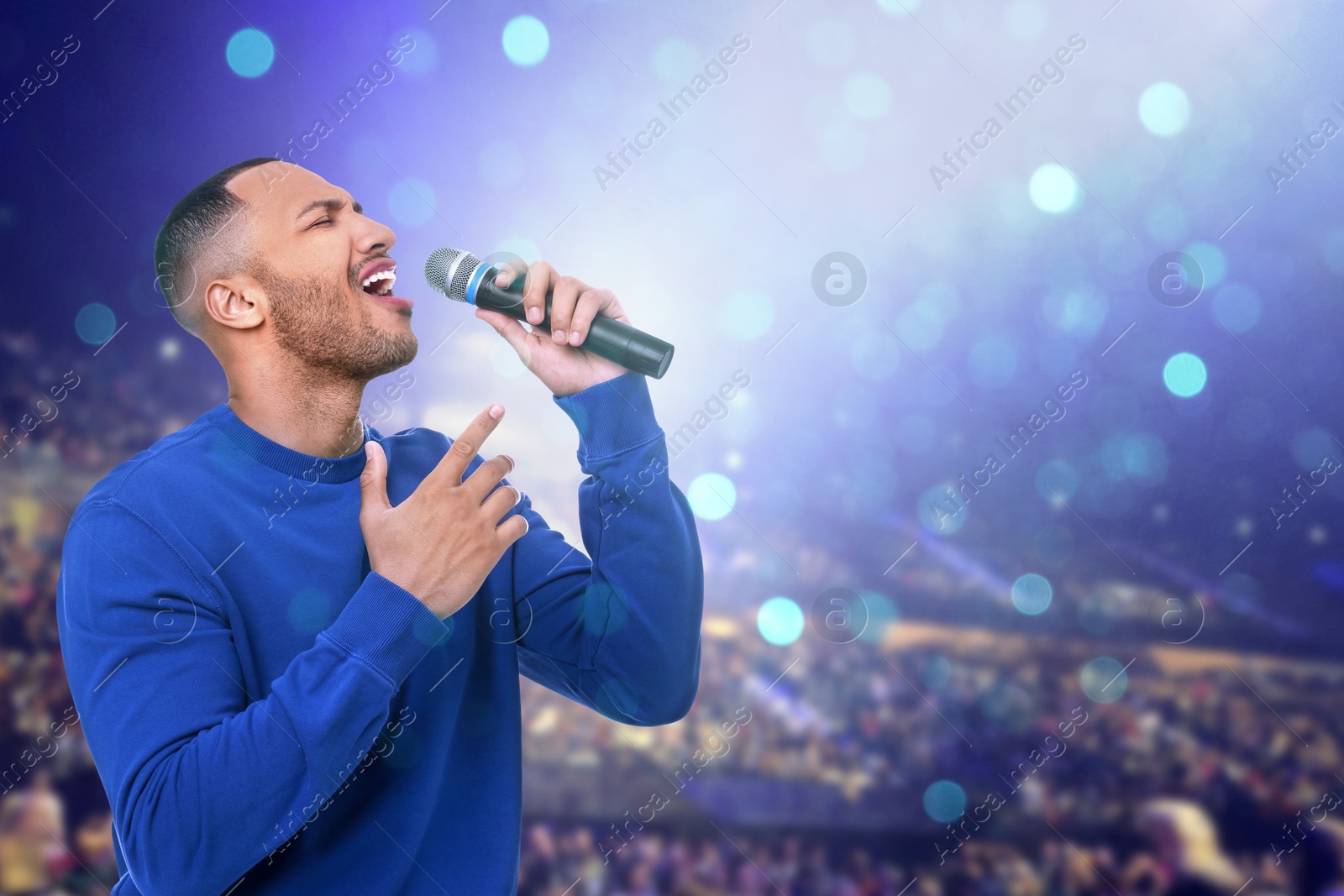 Man singing on stage of concert hall crowded with people Image of Man singing on stage of concert hall crowded with people
