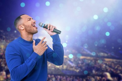 Image of Man singing on stage of concert hall crowded with people