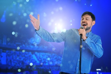 Image of Man singing on stage of concert hall crowded with people