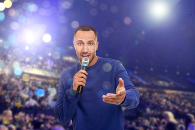 Image of Man singing on stage of concert hall crowded with people