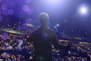 Image of Man performing on stage of concert hall crowded with people