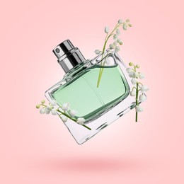 Image of Lilies of the valley and bottle of perfume in air on pink background