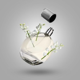 Image of Lilies of the valley and bottle of perfume in air on grey background
