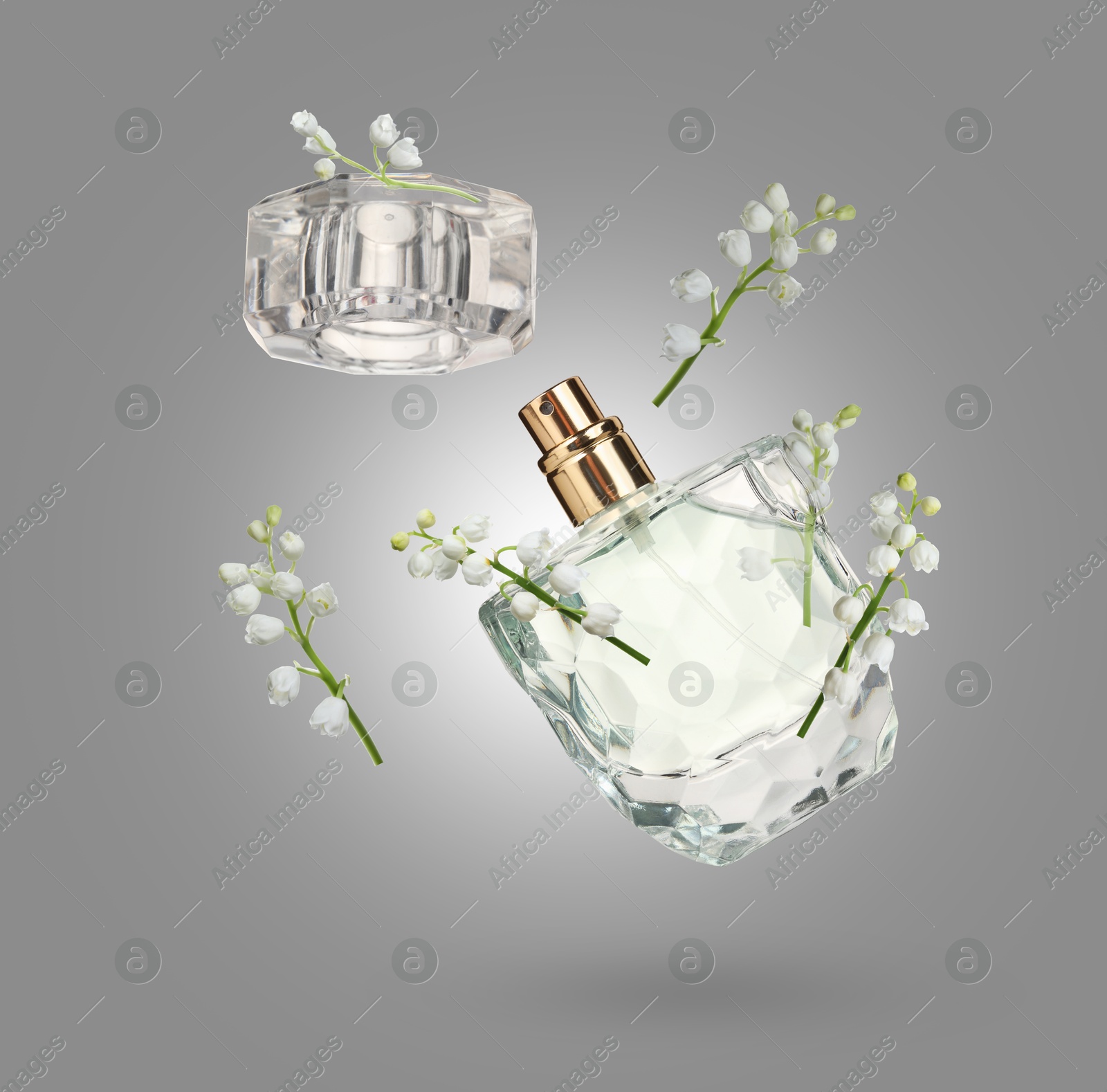 Lilies of the valley and bottle of perfume in air on grey background Image of Lilies of the valley and bottle of perfume in air on grey background