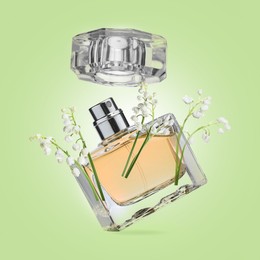 Image of Lilies of the valley and bottle of perfume in air on light green background