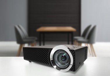 Image of Modern video projector on white table in conference room