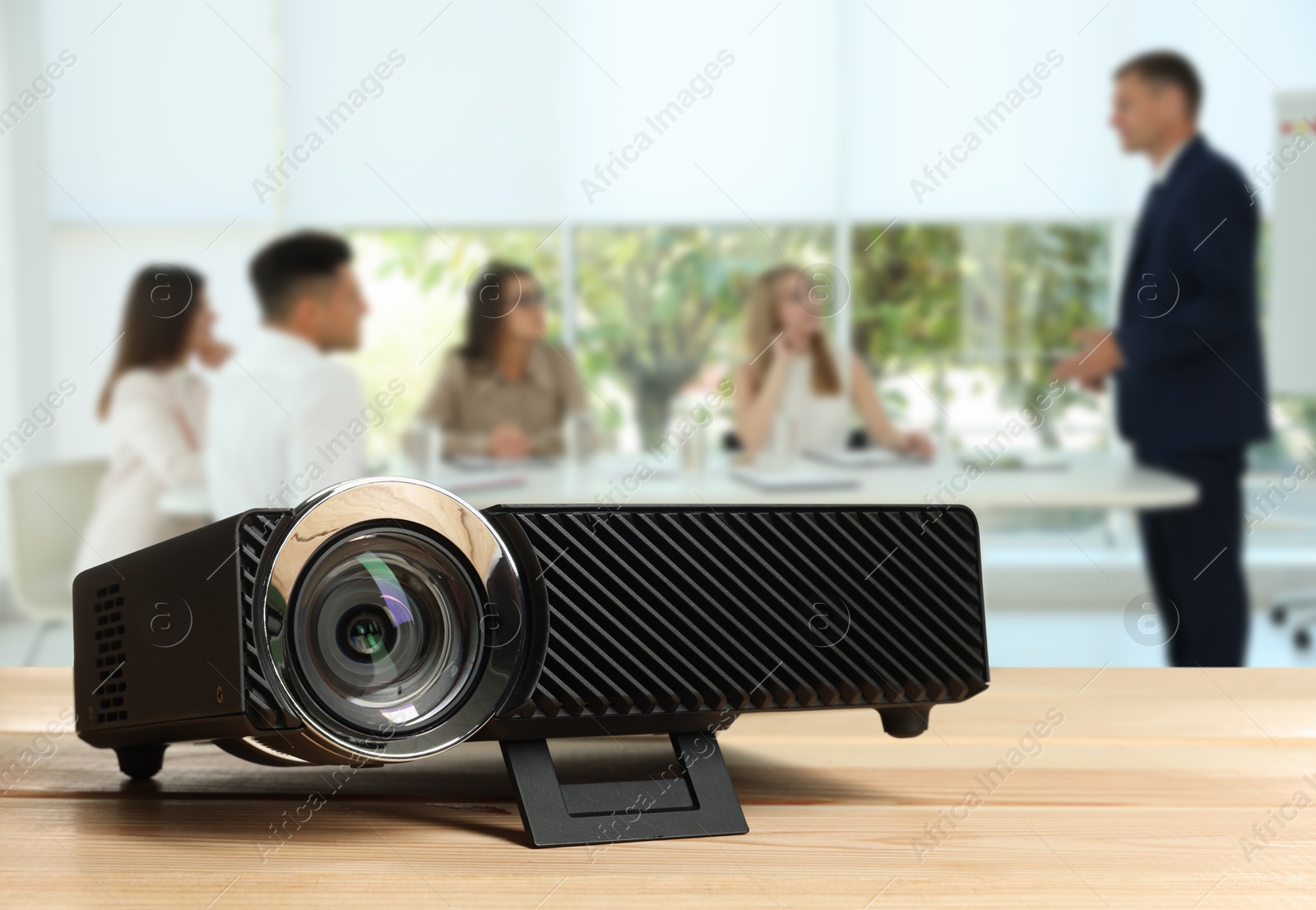 Modern video projector on wooden table and people working in conference room, selective focus Image of Modern video projector on wooden table and people working in conference room, selective focus