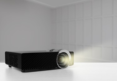 Image of Modern video projector on white table in room
