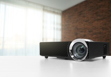 Image of Modern video projector on white table in room