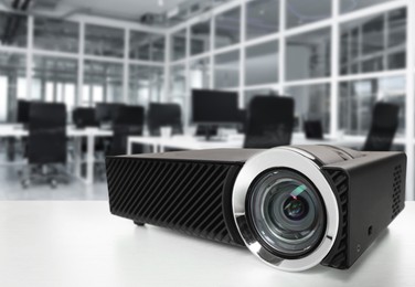 Image of Modern video projector on white table in office