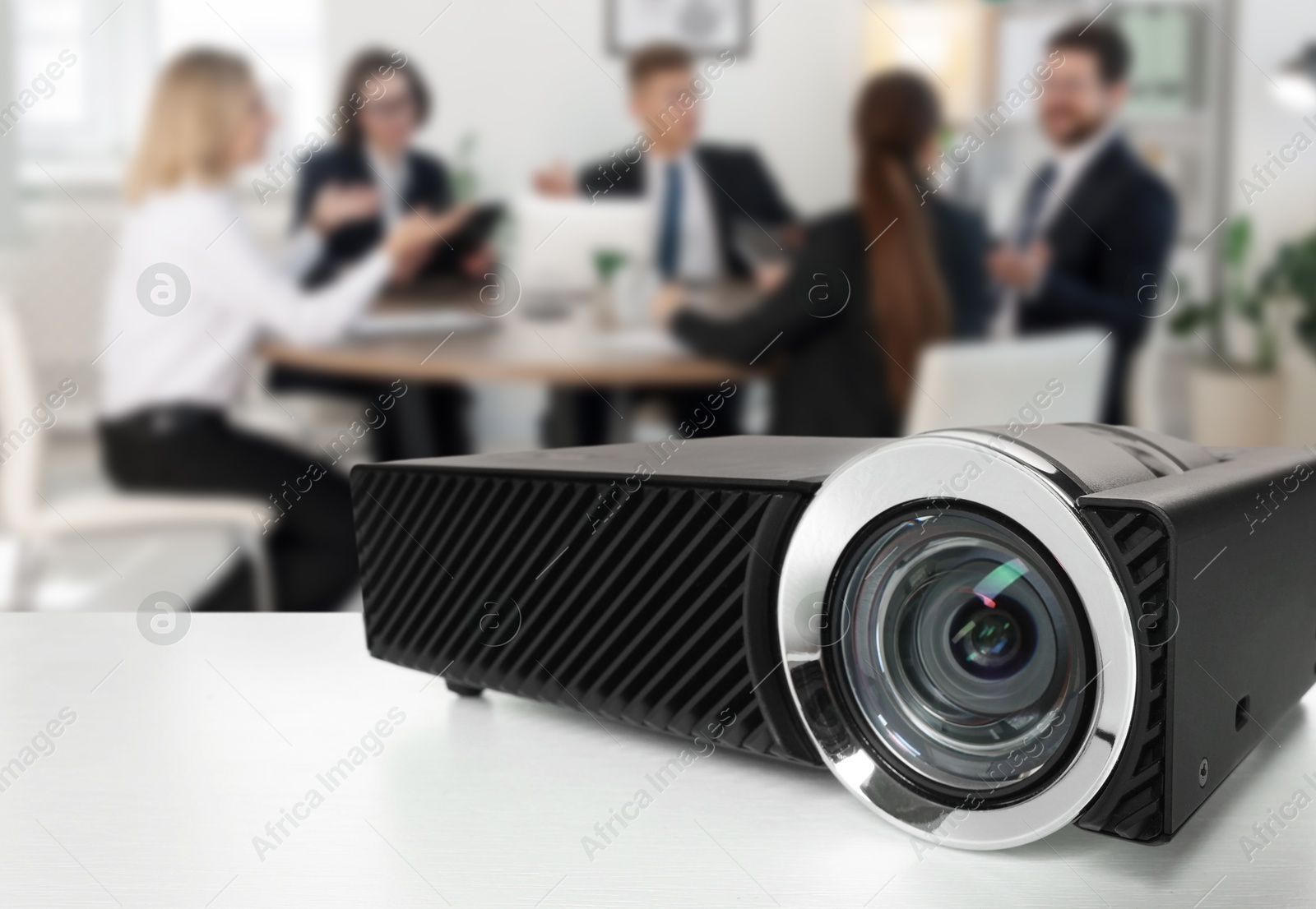 Modern video projector on white table and people working in conference room, selective focus Image of Modern video projector on white table and people working in conference room, selective focus