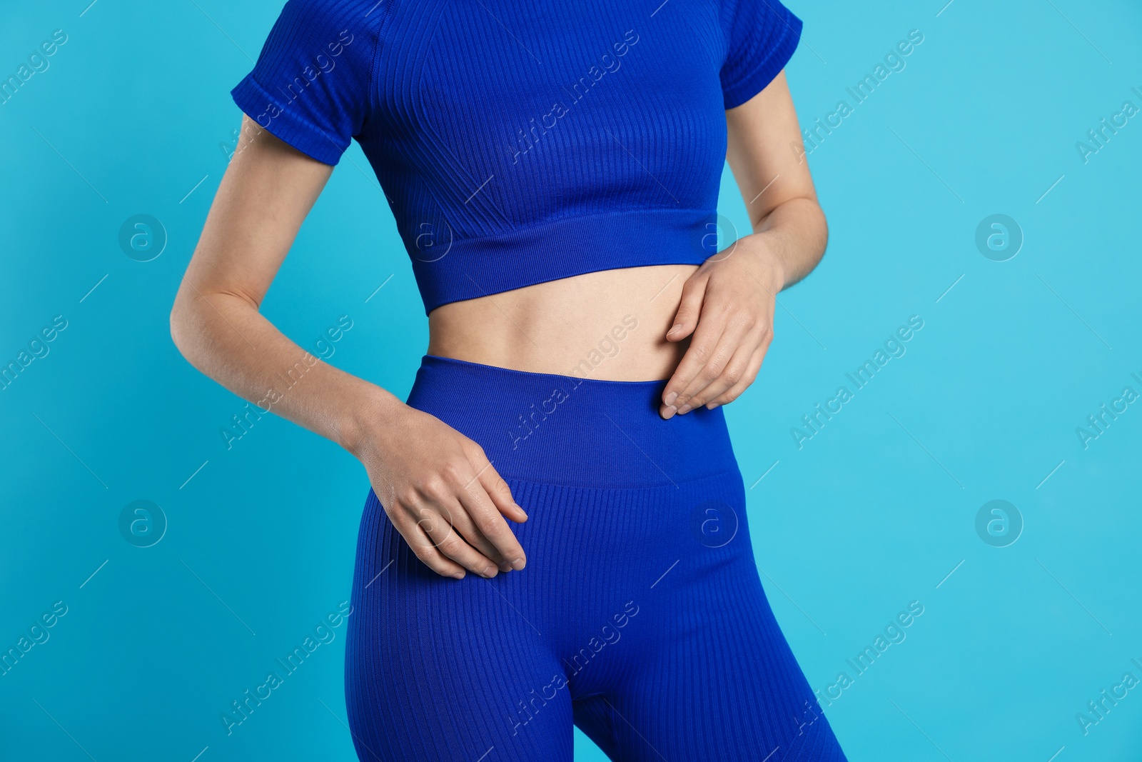 Woman with flat belly on light blue background closeup Photo of Woman with flat belly on light blue background closeup