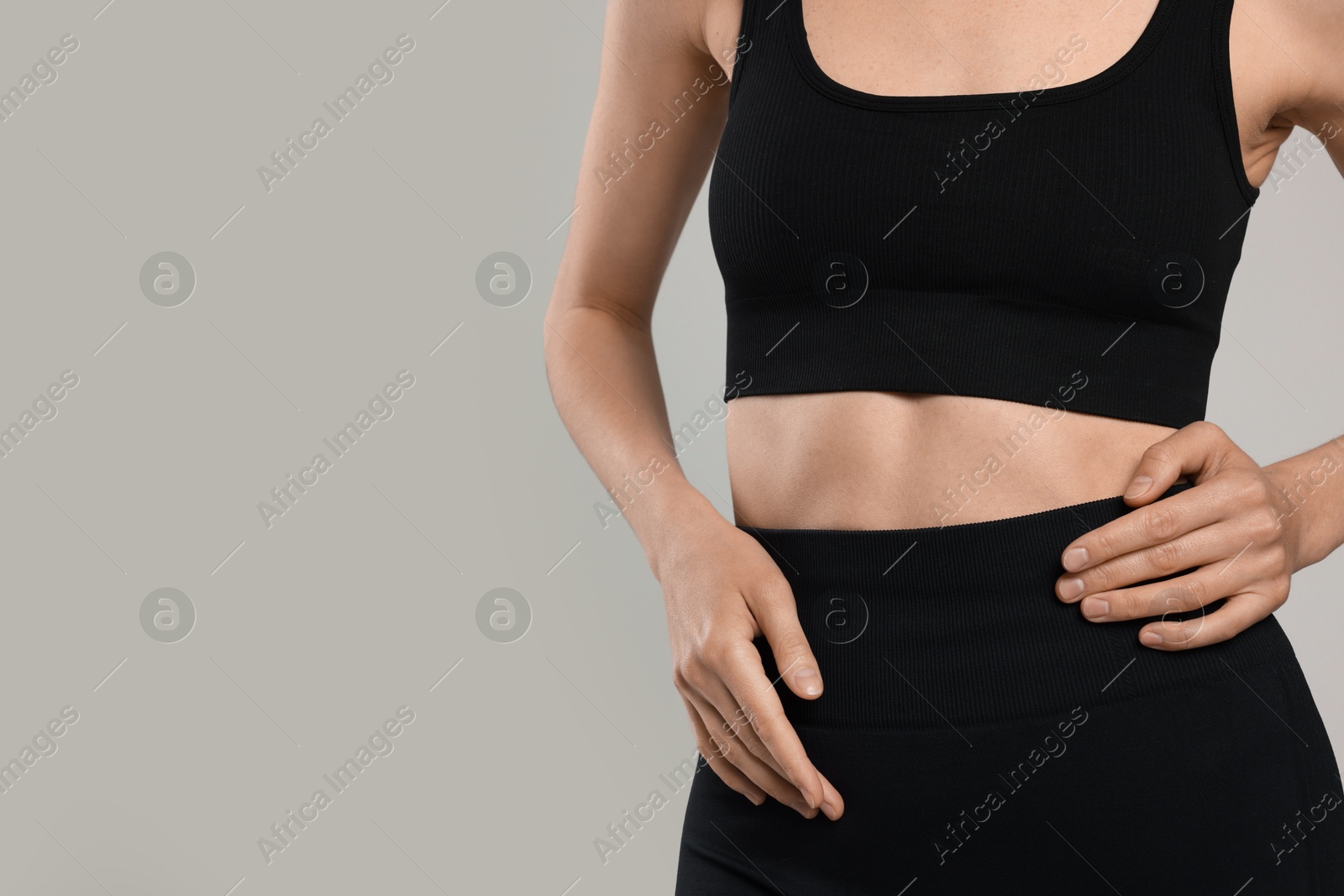 Beautiful woman with flat belly on gray background, closeup. Space for text Photo of Beautiful woman with flat belly on gray background, closeup. Space for text