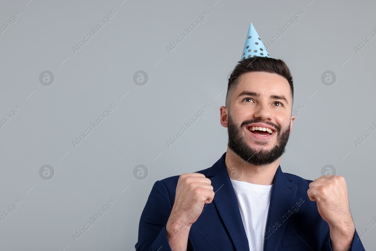 Happy Birthday. Handsome man with party hat on grey background, space for text Photo of Happy Birthday. Handsome man with party hat on grey background, space for text