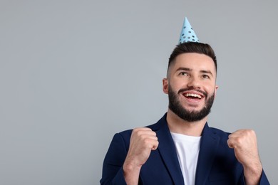 Photo of Happy Birthday. Handsome man with party hat on grey background, space for text