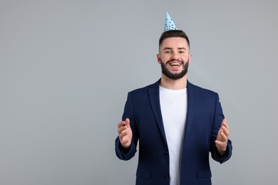 Photo of Happy Birthday. Handsome man with party hat on grey background, space for text