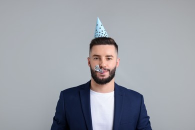 Photo of Happy Birthday. Handsome man with party hat and blower on grey background