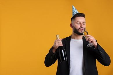Photo of Happy Birthday. Handsome man with party hat and champagne on orange background, space for text