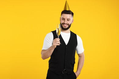 Photo of Happy Birthday. Handsome man with party hat and glass of champagne on orange background