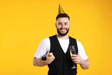 Photo of Happy Birthday. Handsome man with party hat and champagne on orange background