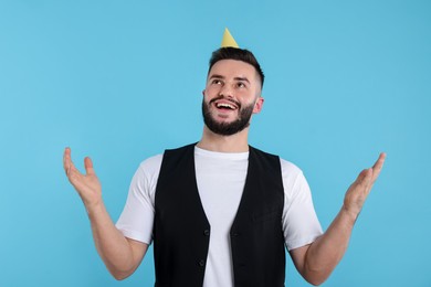 Photo of Happy Birthday. Handsome man with party hat on light blue background