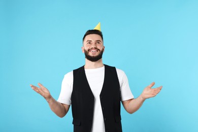 Photo of Happy Birthday. Handsome man with party hat on light blue background