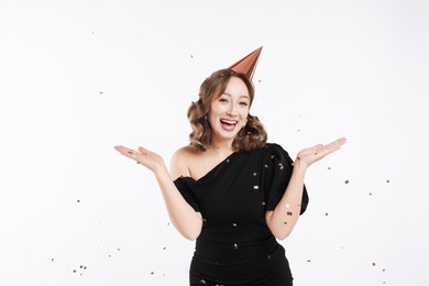 Photo of Birthday celebration. Woman with party cone and confetti on white background