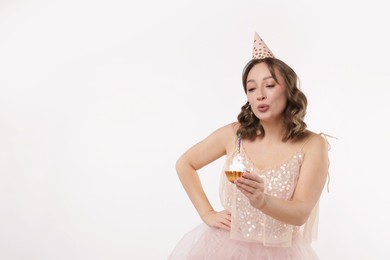 Photo of Birthday celebration. Woman blowing candle on cupcake against white background. Space for text