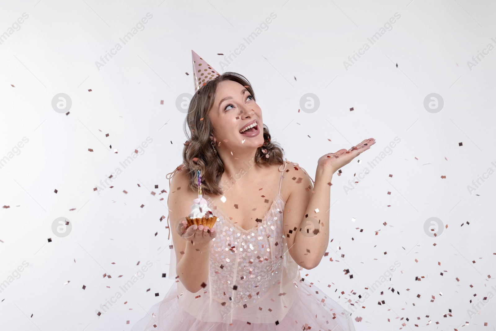 Birthday celebration. Woman with cupcake and confetti on white background Photo of Birthday celebration. Woman with cupcake and confetti on white background