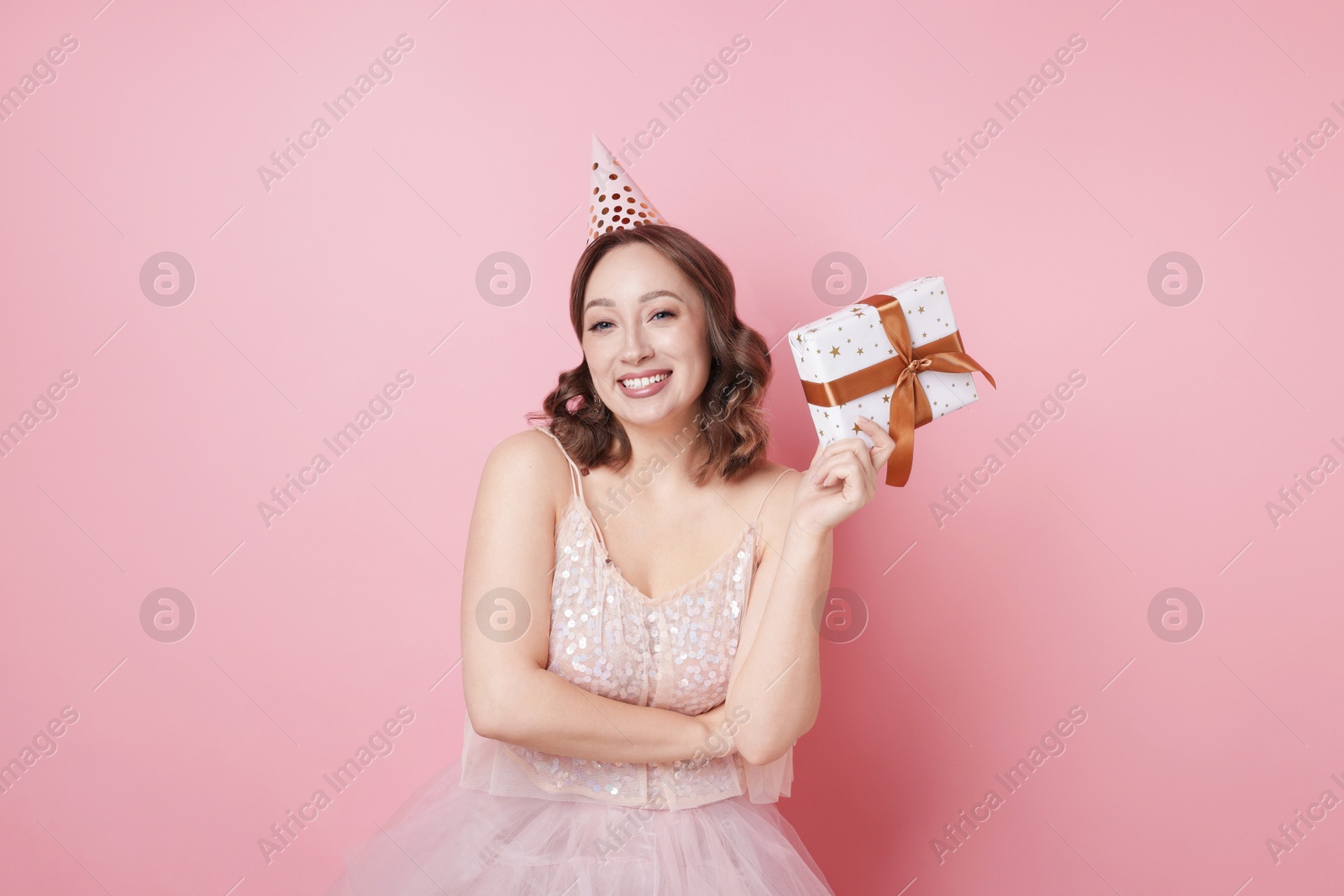 Birthday celebration. Woman with gift on pink background Photo of Birthday celebration. Woman with gift on pink background
