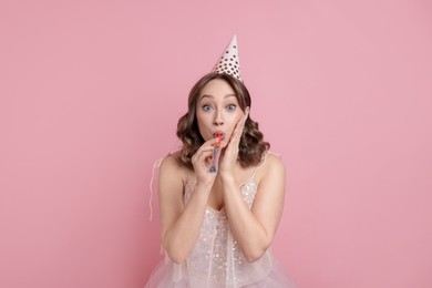 Photo of Birthday celebration. Woman with party horn on pink background