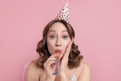 Photo of Birthday celebration. Woman with party horn on pink background