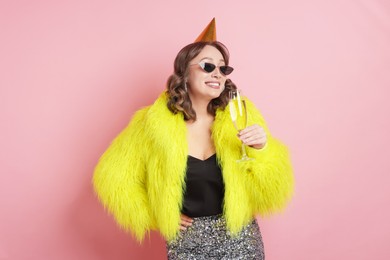 Photo of Birthday celebration. Woman with glass of sparkling wine on pink background