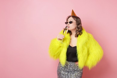 Photo of Birthday celebration. Woman with glass of sparkling wine on pink background. Space for text