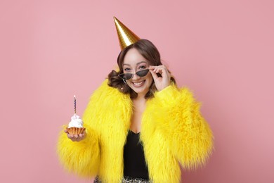 Photo of Birthday celebration. Woman with cupcake on pink background
