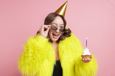 Photo of Birthday celebration. Woman with cupcake on pink background