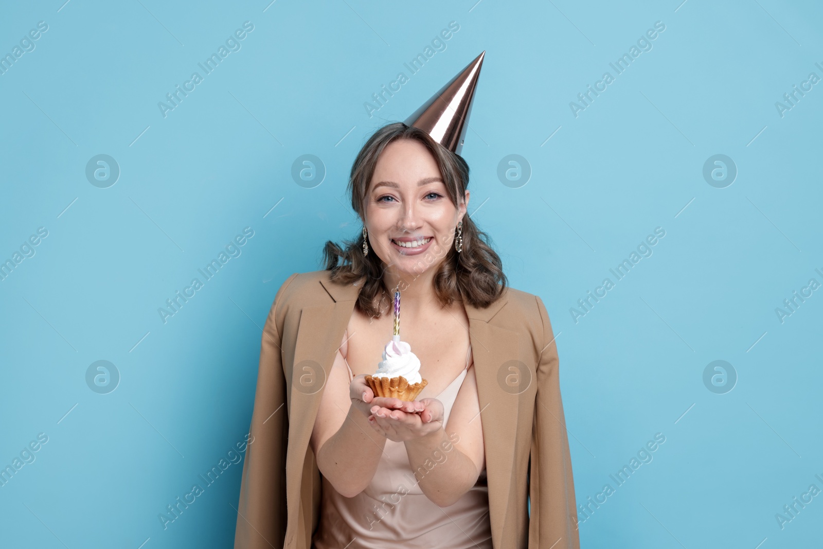 Birthday celebration. Woman with cupcake on light blue background Photo of Birthday celebration. Woman with cupcake on light blue background