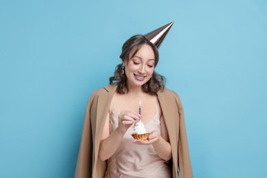 Photo of Birthday celebration. Woman with cupcake on light blue background