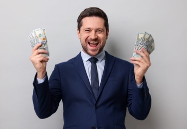 Photo of Happy greedy banker with dollar banknotes on grey background