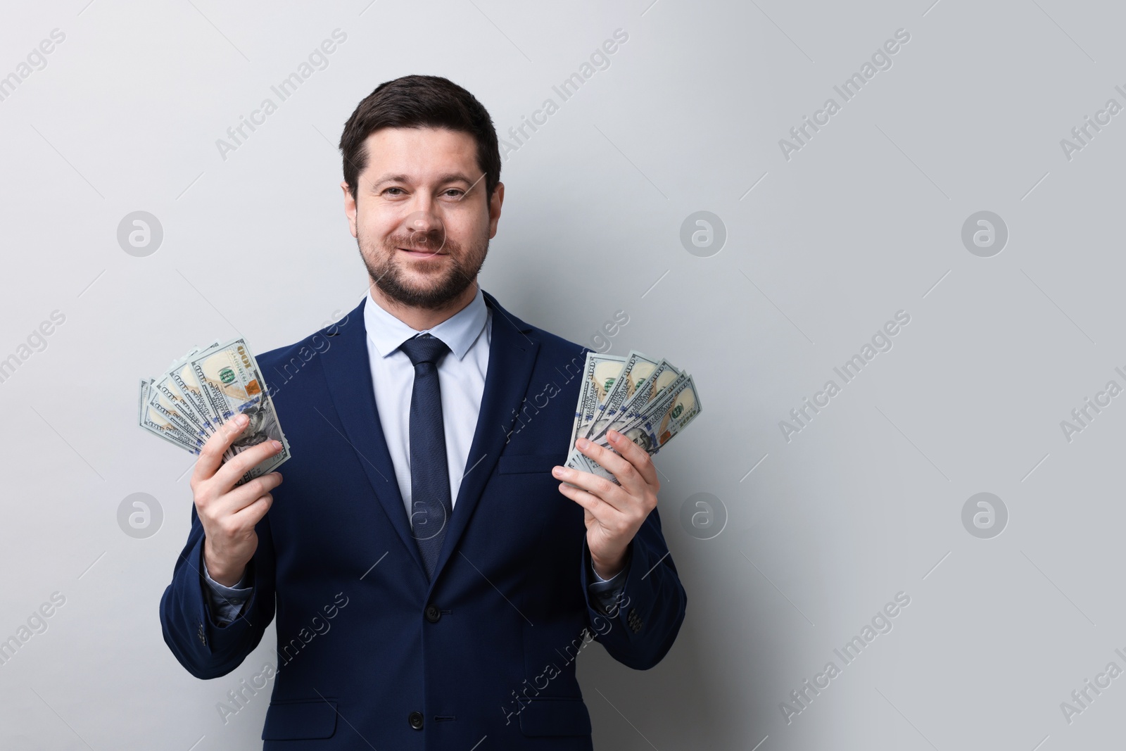 Greedy banker with dollar banknotes on grey background. Space for text Photo of Greedy banker with dollar banknotes on grey background. Space for text