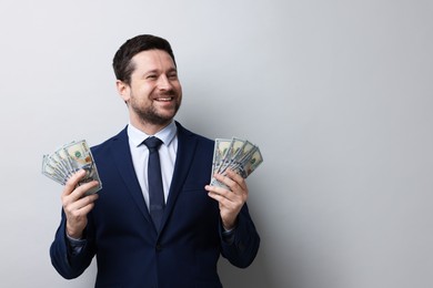Photo of Happy greedy banker with dollar banknotes on grey background. Space for text